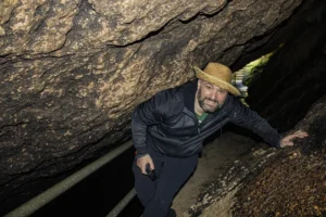 Josemi caminando de lado entre rocas en el Interior de la Cueva de las Aguas de Novales