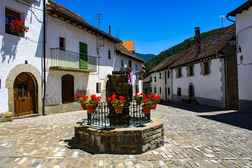 Plaza empedrada en Ansó con una fuente en medio decorada con flores